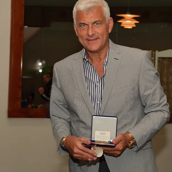 A man in a suit holding a commemorative plaque. 
